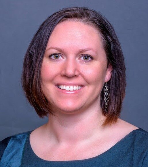 Megan Wibbell, VP of Integration and Implementation smiling in a blue shirt in front of a blue background,